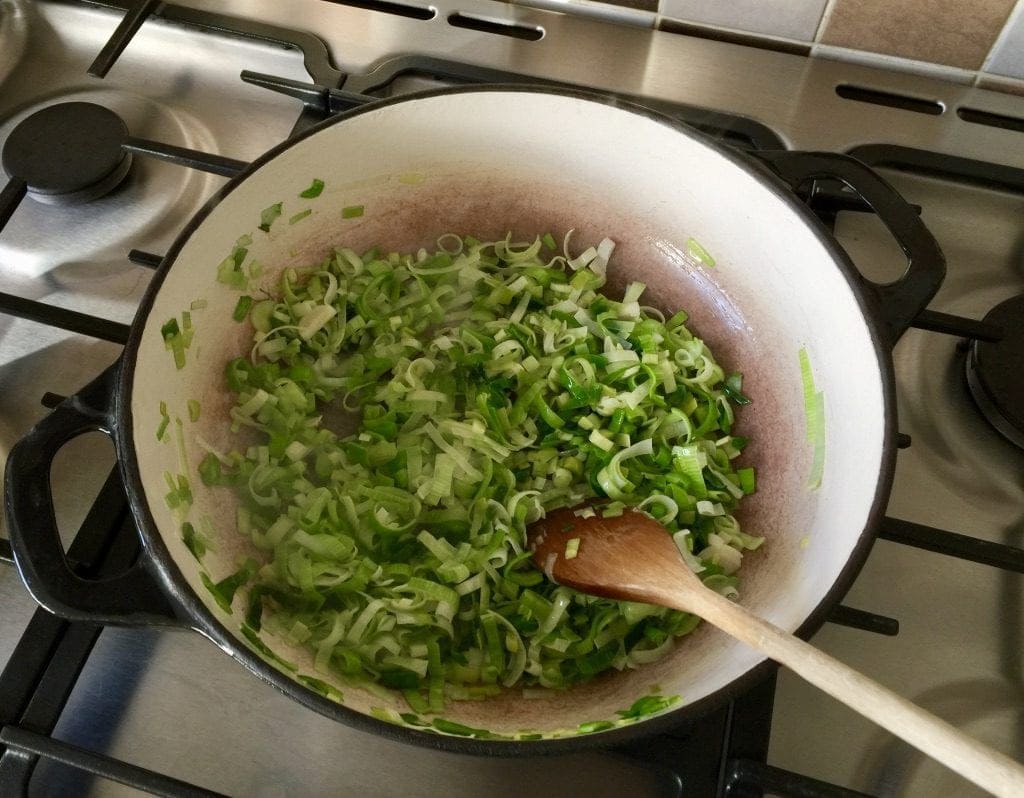 Leeks being sauteed in a pan.