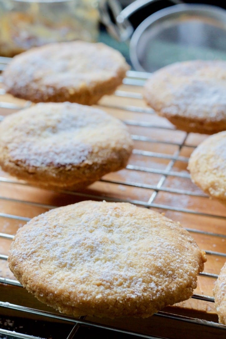 Mince pies sprinkled with icing sugar on a cooling rack.