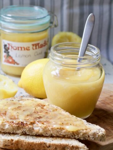 Lemon curd in a jar with a spoon and on toast.