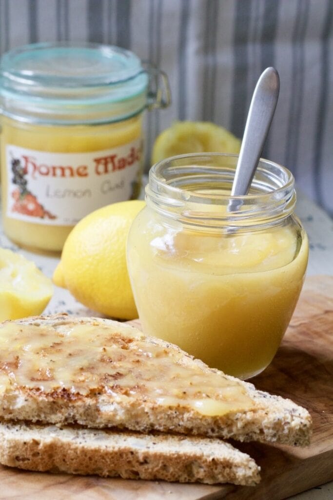 Lemon curd in a jar with a spoon and on toast.