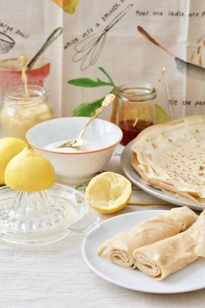 Pancakes spread on the table with lemon juice, sugar, jam, lemon curd.