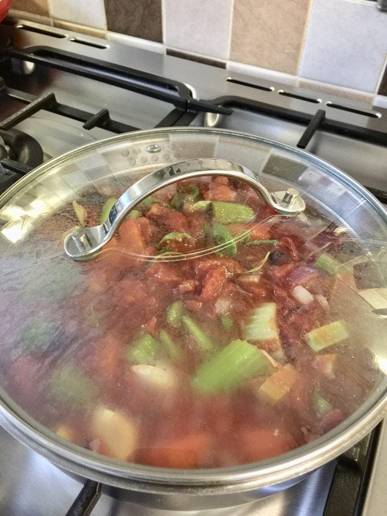 Vegetables simmering in a covered pan.