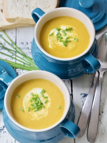 Two bowls filled with Jerusalem artichoke soup & garnishes.