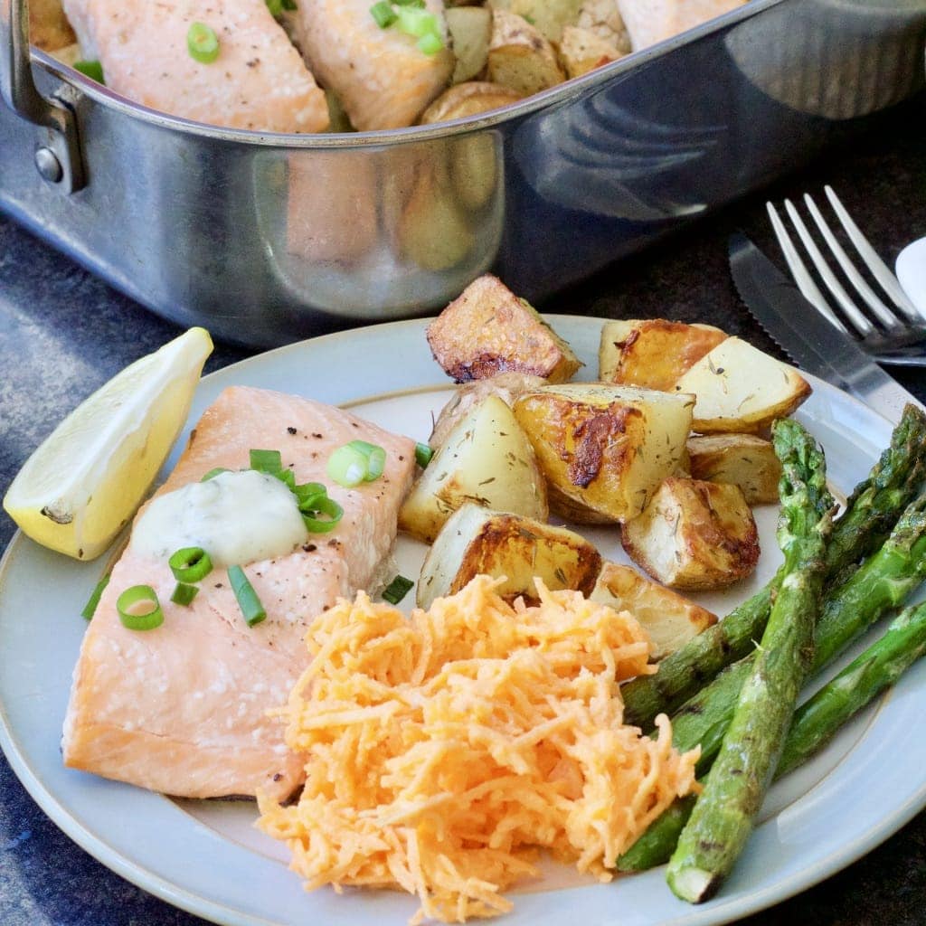 Fish, potatoes, carrot salad & asparagus on a plate.