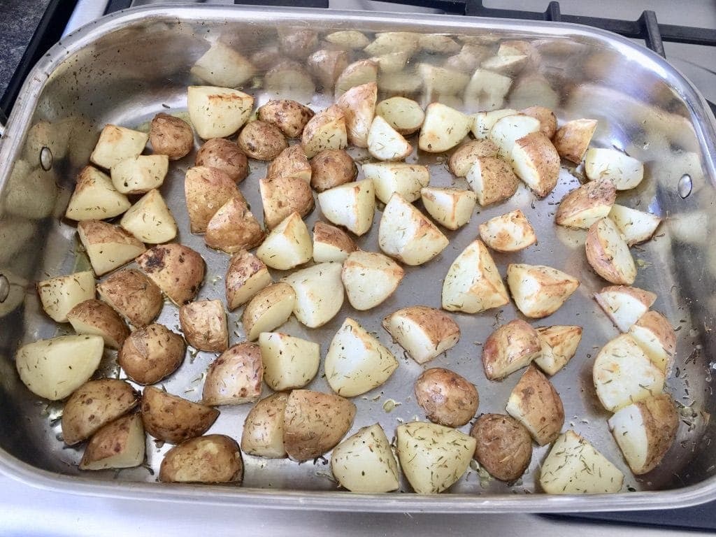 Partially roasted new potatoes in a tray.