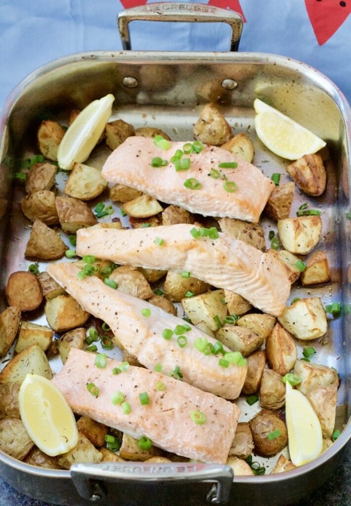 Roasting tray with potatoes, salmon & lemon wedges.