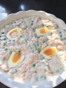 Fish pie filling in a dish topped with 4 egg halves.