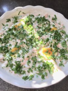 Fish pie filling in a dish covered in chopped parsley.