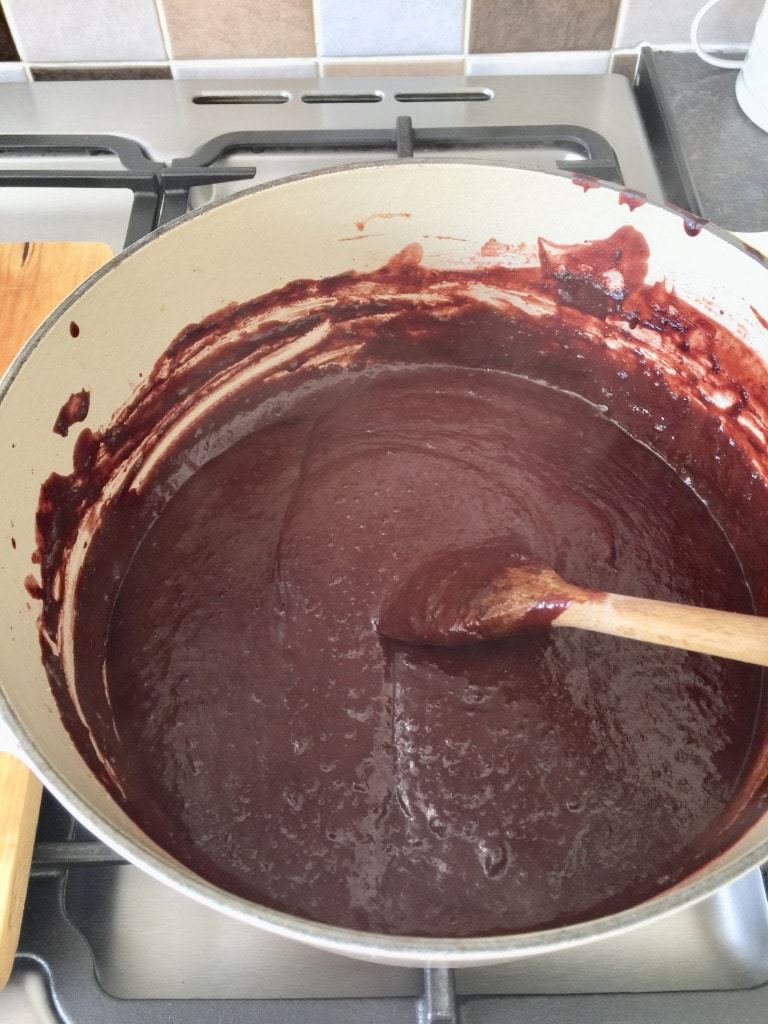 Pureed plum jam simmering in a pot.