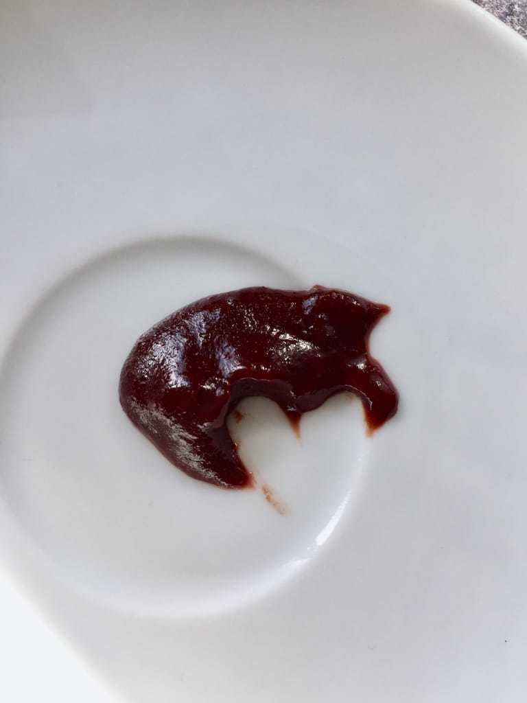 Dollop of plum jam on a white saucer.
