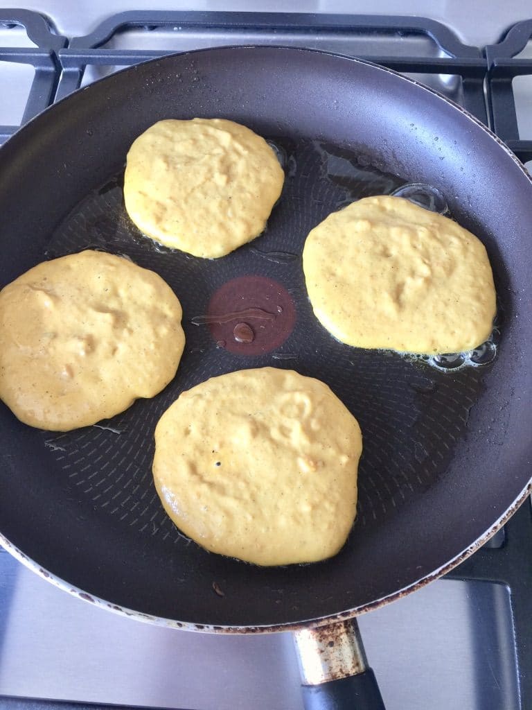4 pancakes frying in a pan.