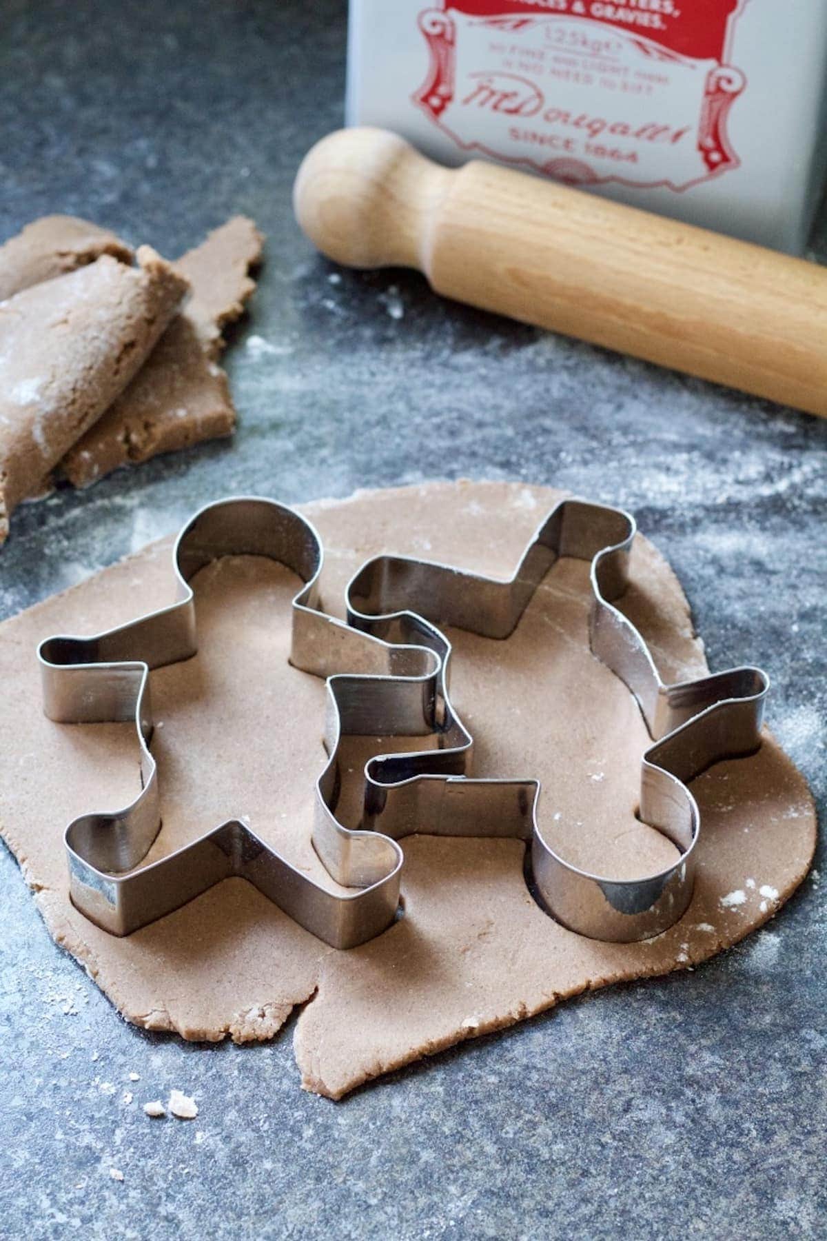 Two gingerbread men cutters on top of rolled out dough.