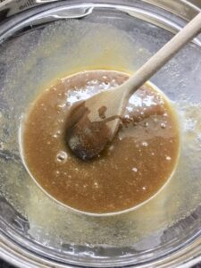 Sugar and butter mix in a bowl with wooden spoon.