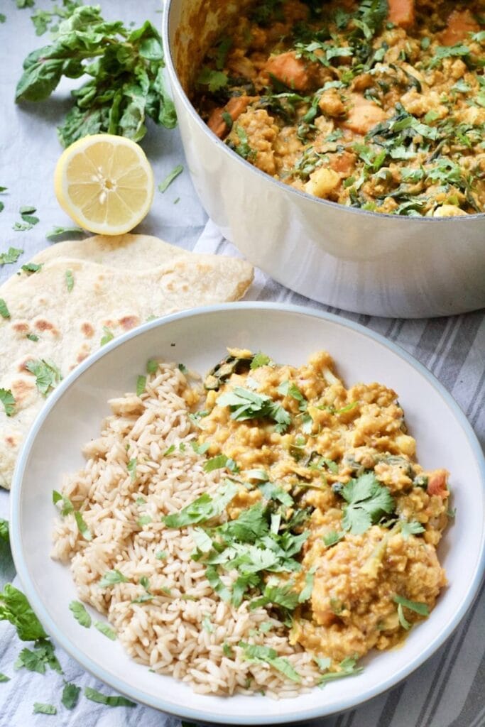 Easy Cauliflower & Lentil Curry - plate of curry and rice standing next to pot full of curry