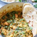 Cauliflower and lentil curry in a pot with some flat bread.