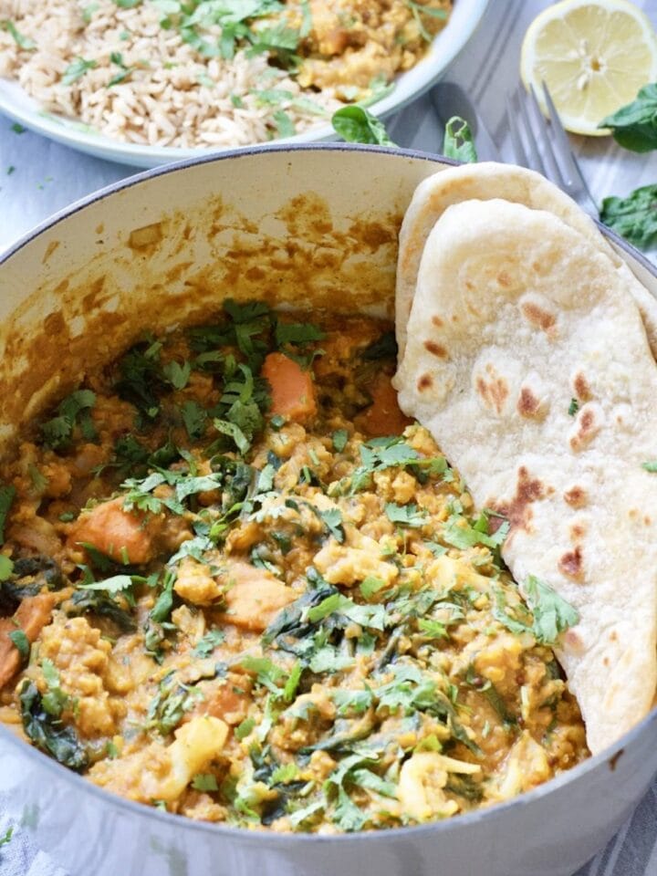 Cauliflower and lentil curry in a pot with some flat bread.