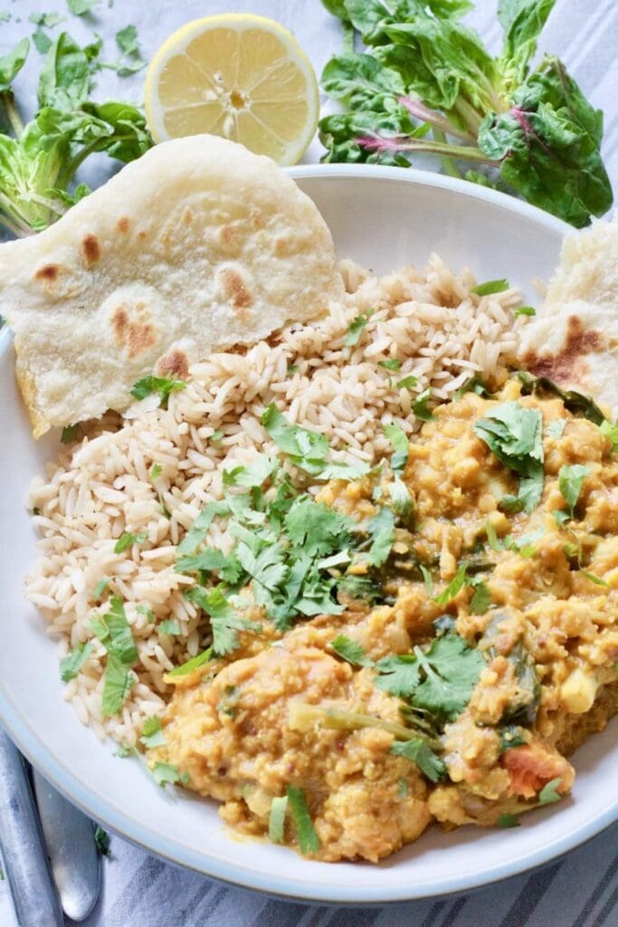 Easy Cauliflower & Lentil Curry - curry plated with rice and flat bread and sprinkled with parsley
