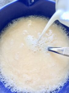 Adding milk to eggs and water in a bowl