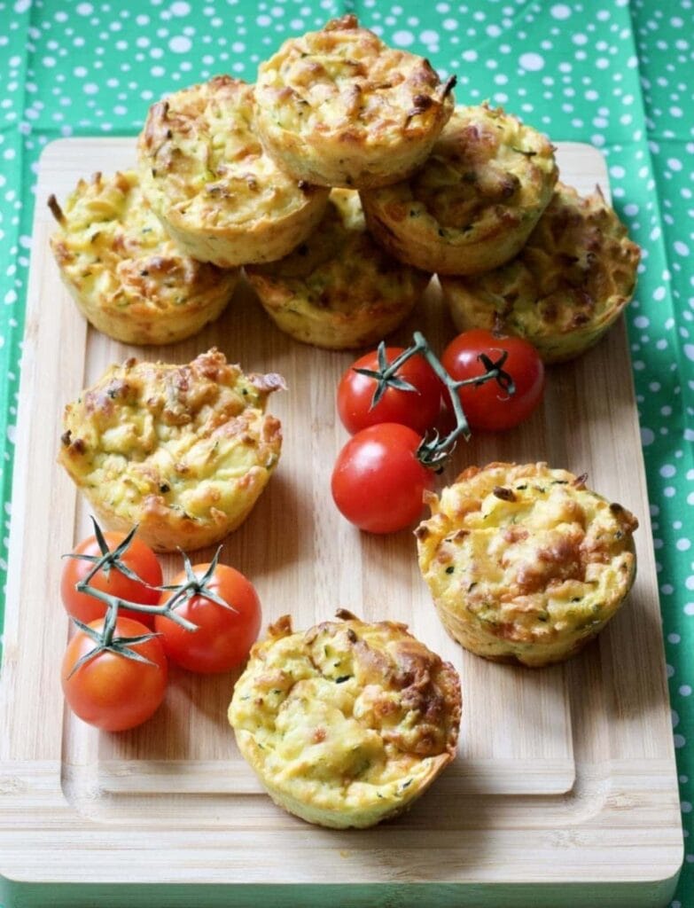 Cheesy Carrot & Courgette Savoury Muffins on the board with cherry tomatoes