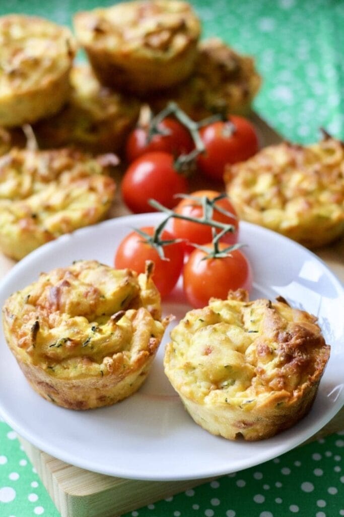 Cheesy Carrot & Courgette Savoury Muffins on a plate with cherry tomatoes