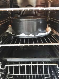 cake tin in the oven with tray full of boiling water underneath
