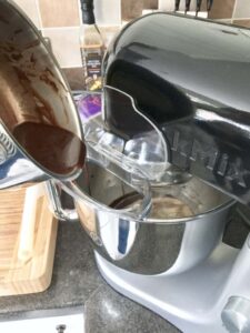 adding melted chocolate to the mixer bowl