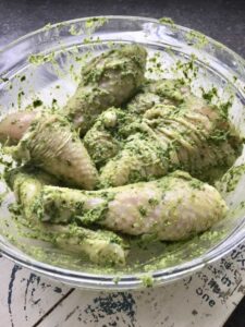 Chicken pieces covered in pesto in a bowl