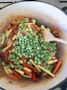 various veggies and frozen peas in a pan