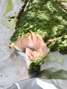 Piece of baked salmon covered in pesto