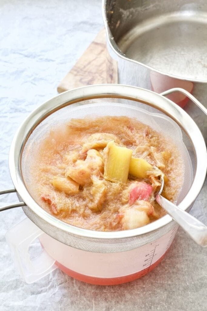 Sieve with rhubarb pulp on top of a jug.