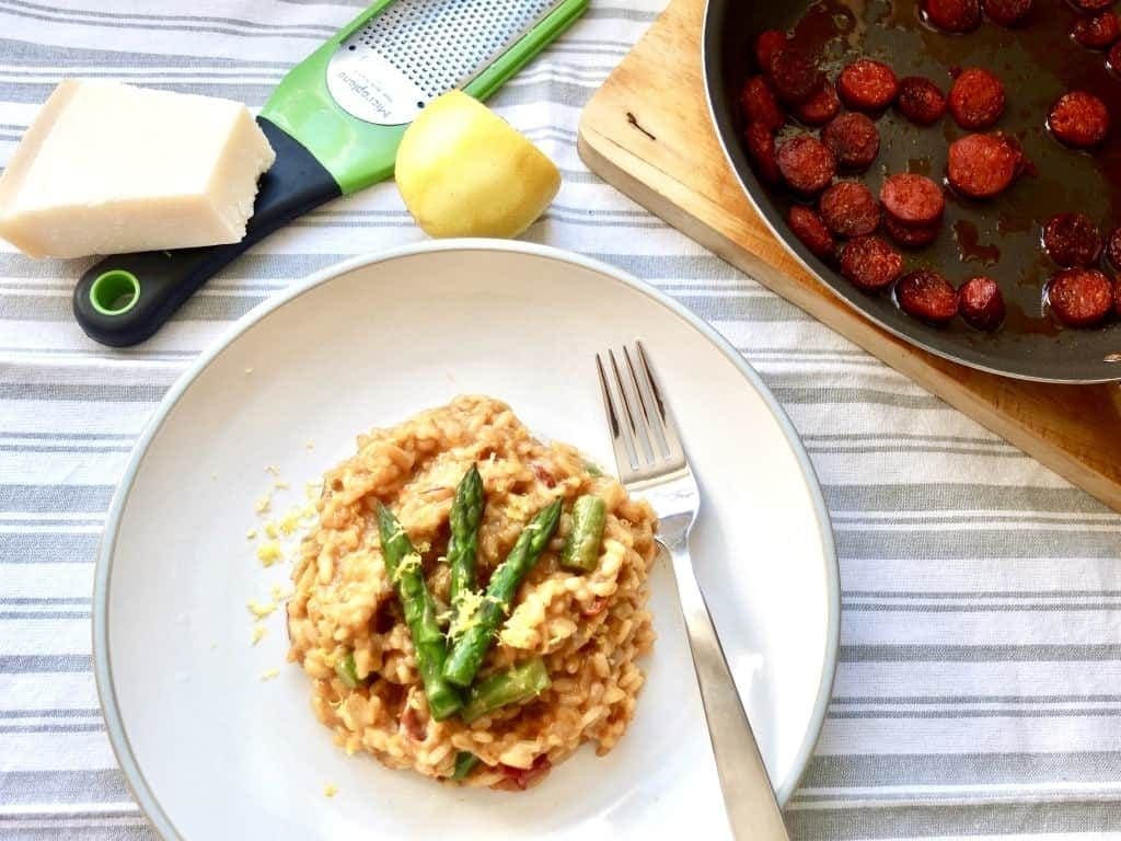 Plate with risotto, grater and pan with chorizo.