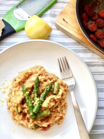 Plate with risotto, grater and pan with chorizo.