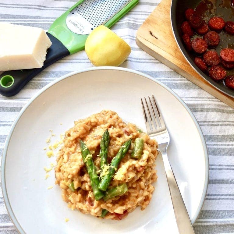 Plate with risotto, grater and pan with chorizo.