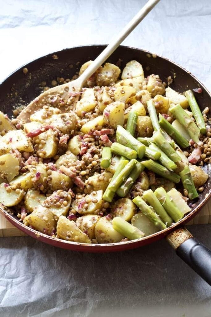 Asparagus chunks with potatoes and lentils in a pan.