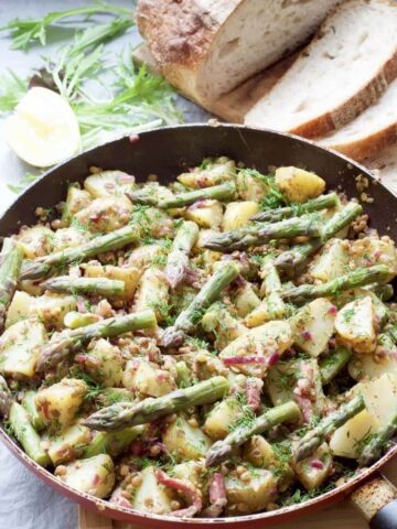 Salad in a pan with asparagus tips on top.