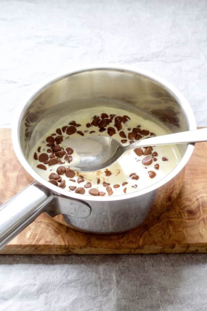 Cream with chocolate chips in a pan on a board.