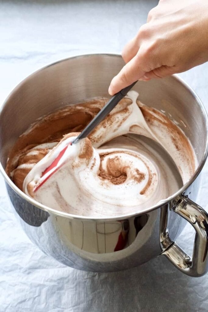 Cocoa powder being folded into the egg whites.