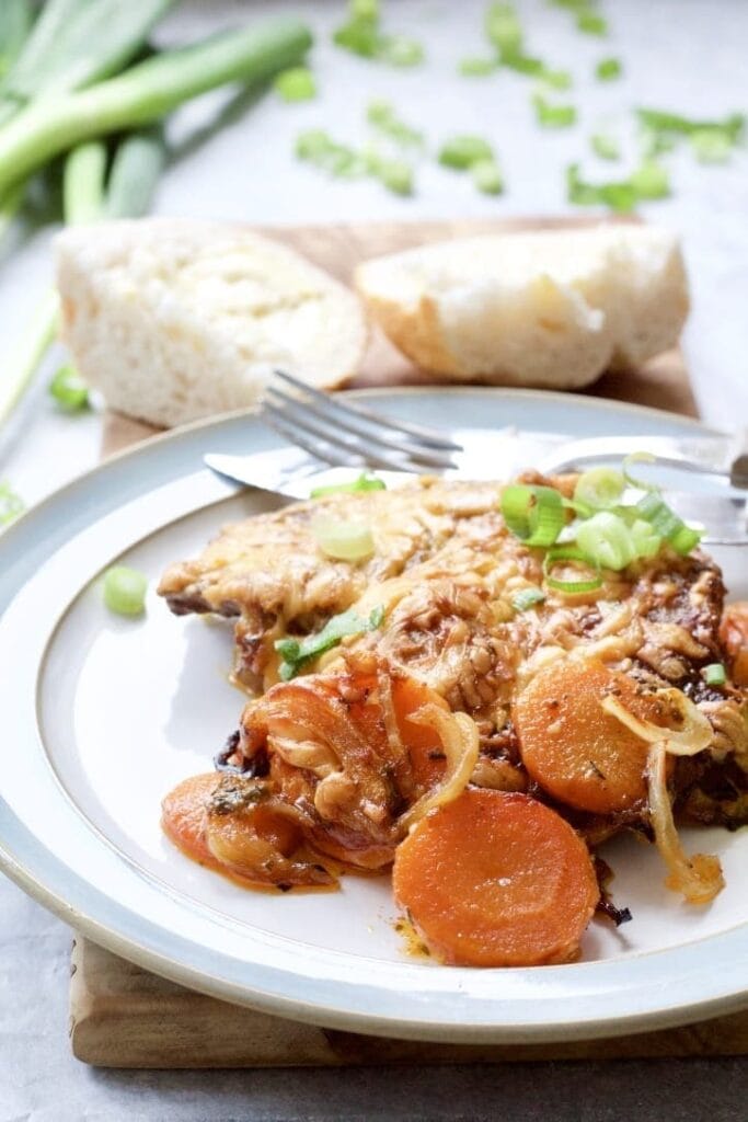 Oven baked pork chops on a plate with carrots.