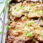 Oven baked pork chops in a baking dish.