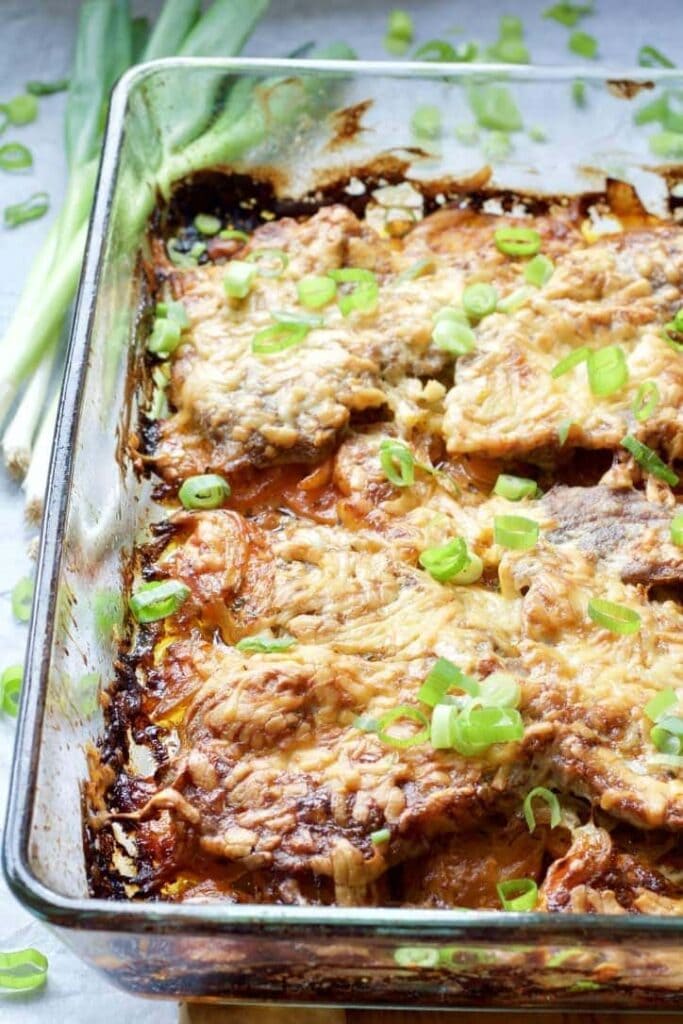 Oven baked pork chops in a baking dish.