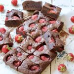 Strawberry brownies on a board with fresh strawberries.