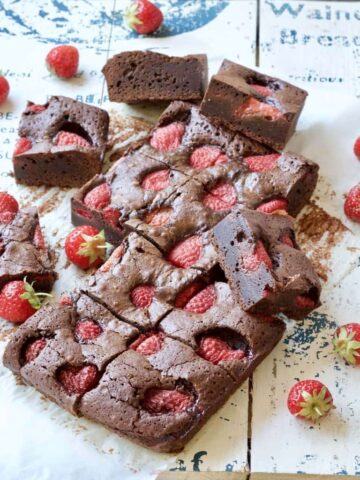 Strawberry brownies on a board with fresh strawberries.