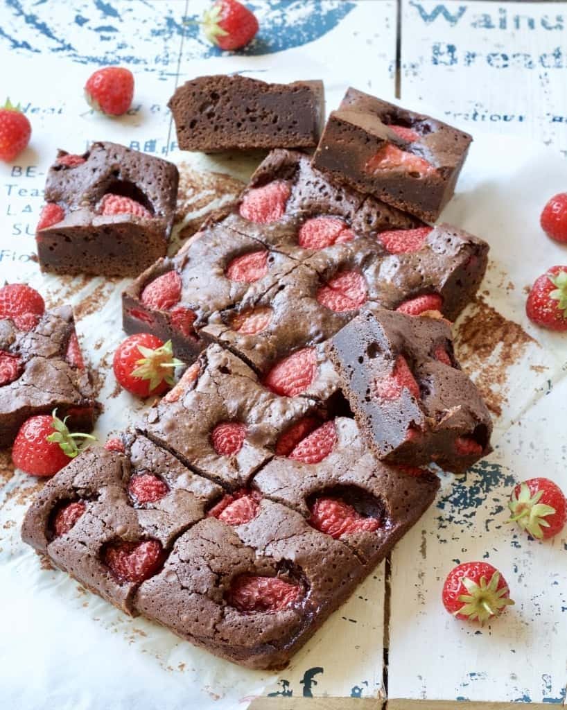 Strawberry brownies on a board with fresh strawberries.