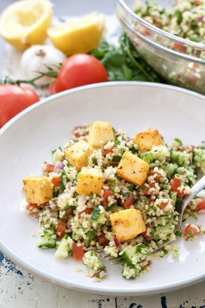 Portion of tabbouleh topped with cheese cubes.