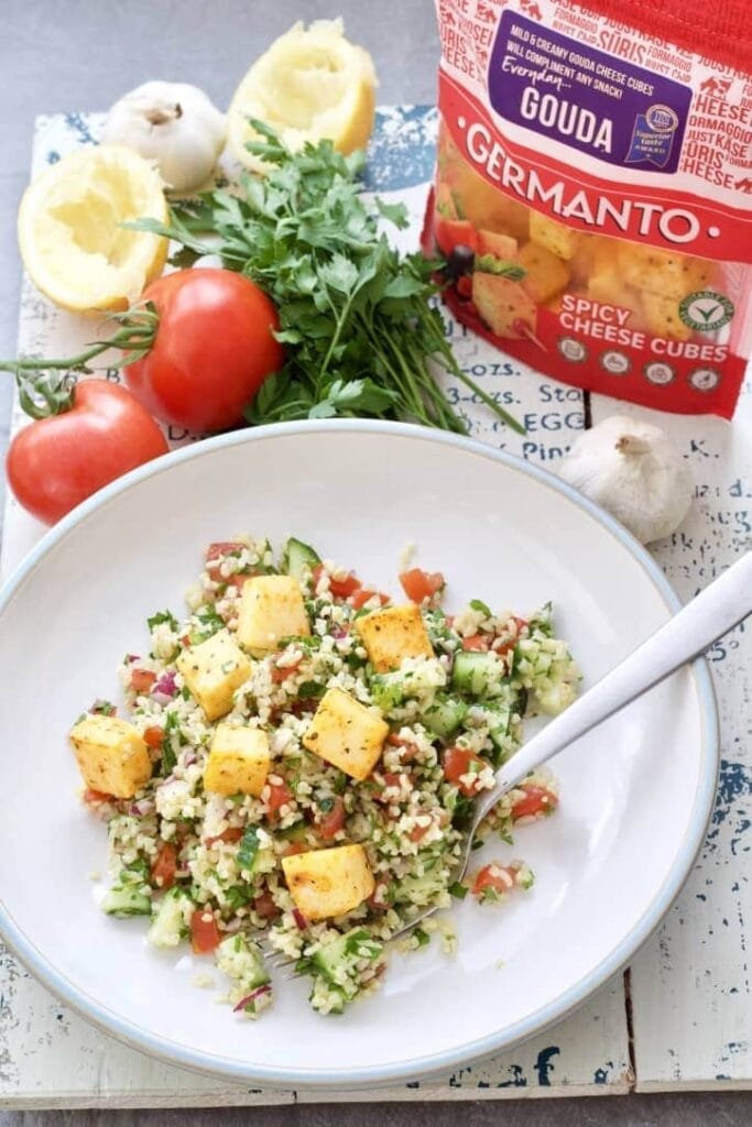 Tabbouleh on a plate topped with cheese cubes.