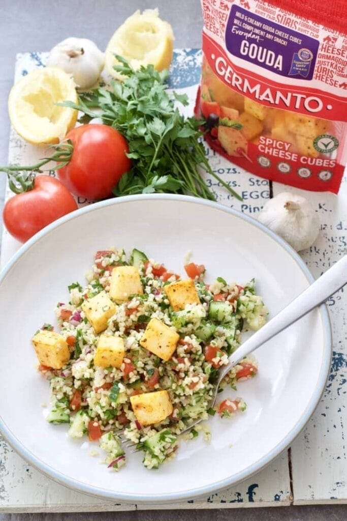 Tabbouleh on a plate topped with cheese cubes.