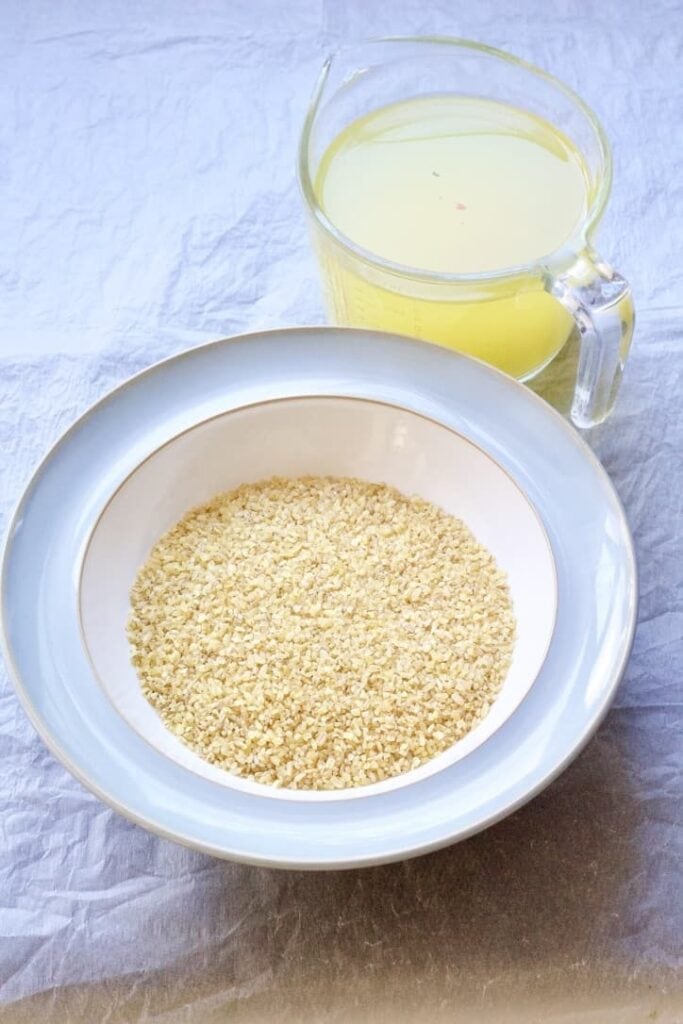 Bulgur wheat in a bowl & stock in a jug.