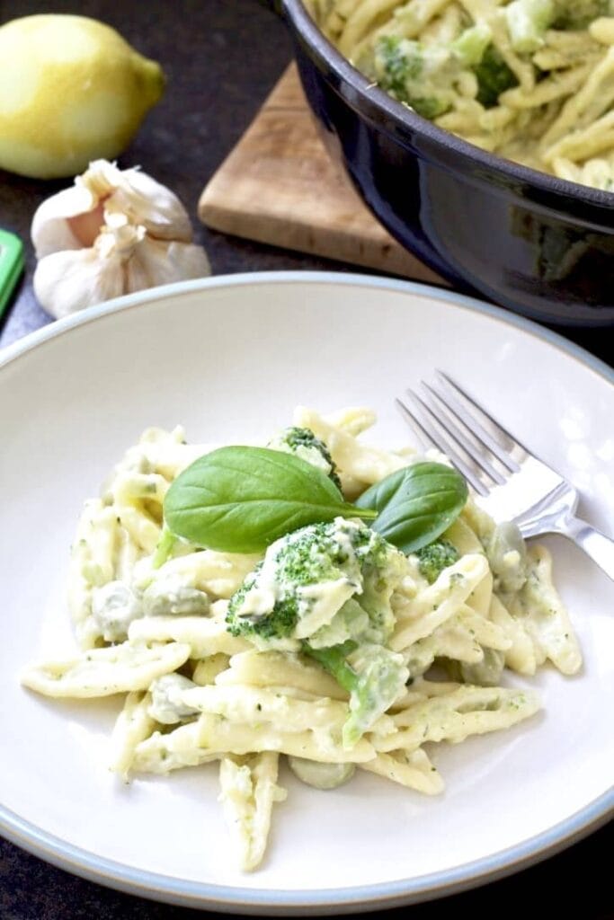 Pasta on a plate with broccoli and basil leaves.