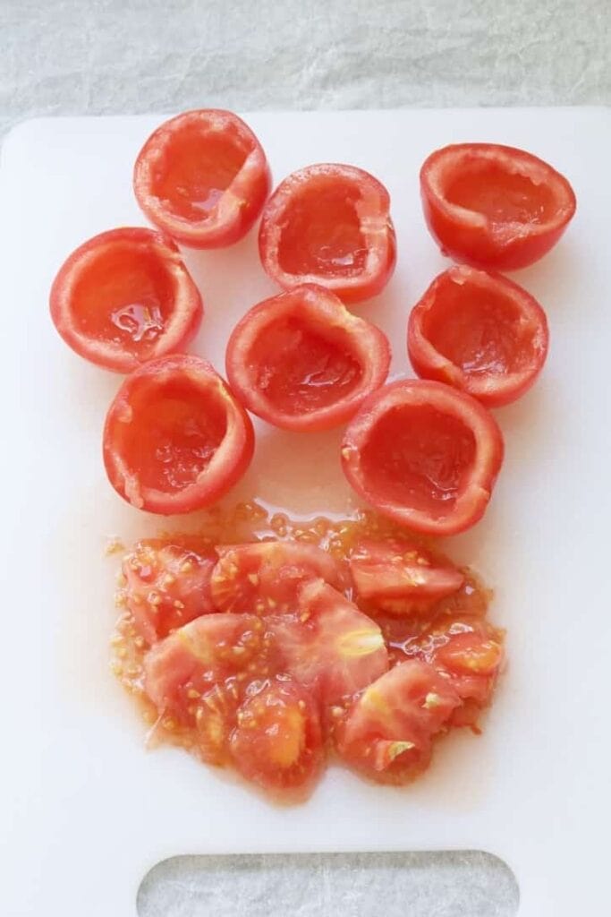 Deseeded tomato halves on a chopping board.