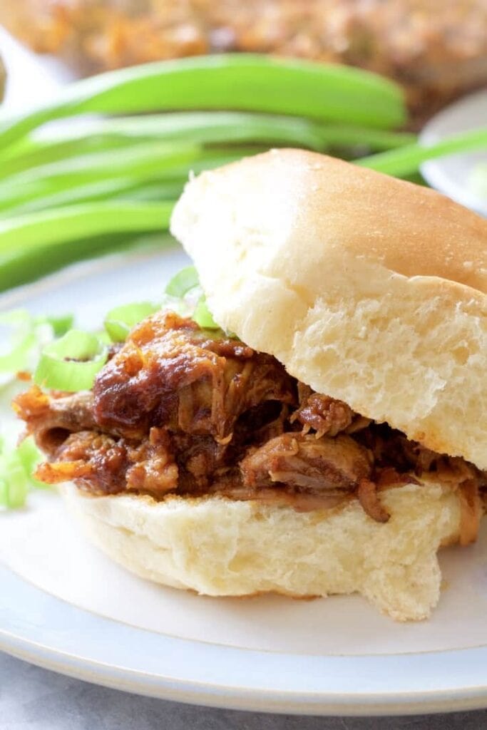 BBQ pulled pork in a bun with top tilted, close up.